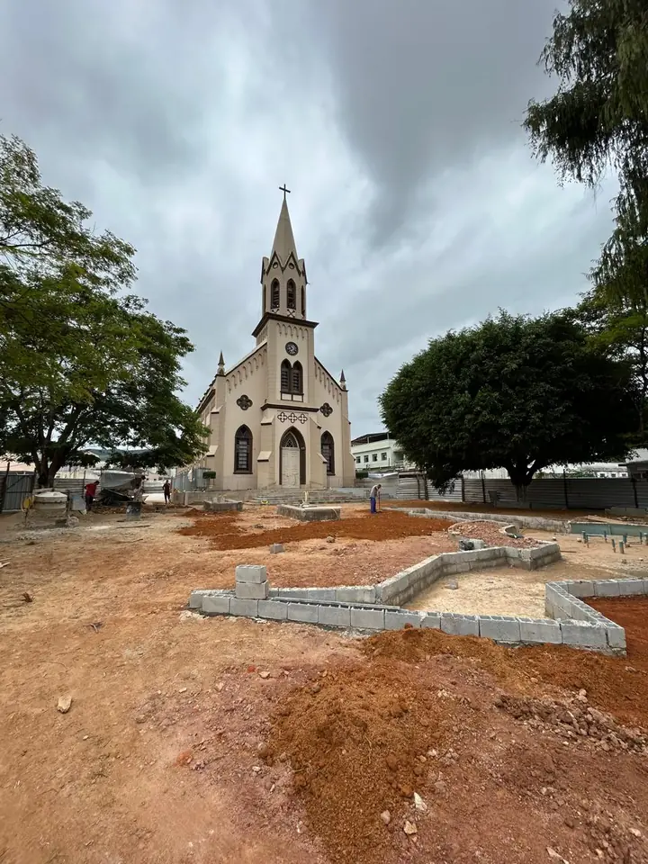 Praça em reforma diante de uma igreja em Mercês, com canteiros de blocos de concreto sendo construídos