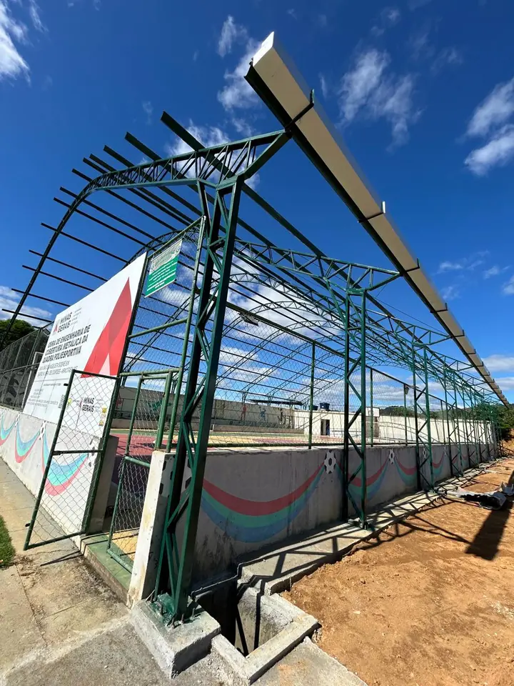Estrutura metálica verde da cobertura de uma quadra poliesportiva em Aracitaba, com placa da obra do Governo de Minas Gerais